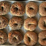 best homemade sourdough bagels sitting on a parchment lined sheet pan.