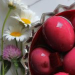 Pickled Eggs sitting in a decorative glass bowl on a plate with wildflowers around it